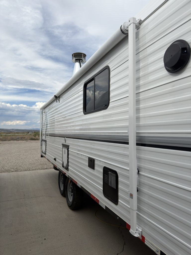 Passenger-side exterior with two windows, storage doors, and tandem axles.