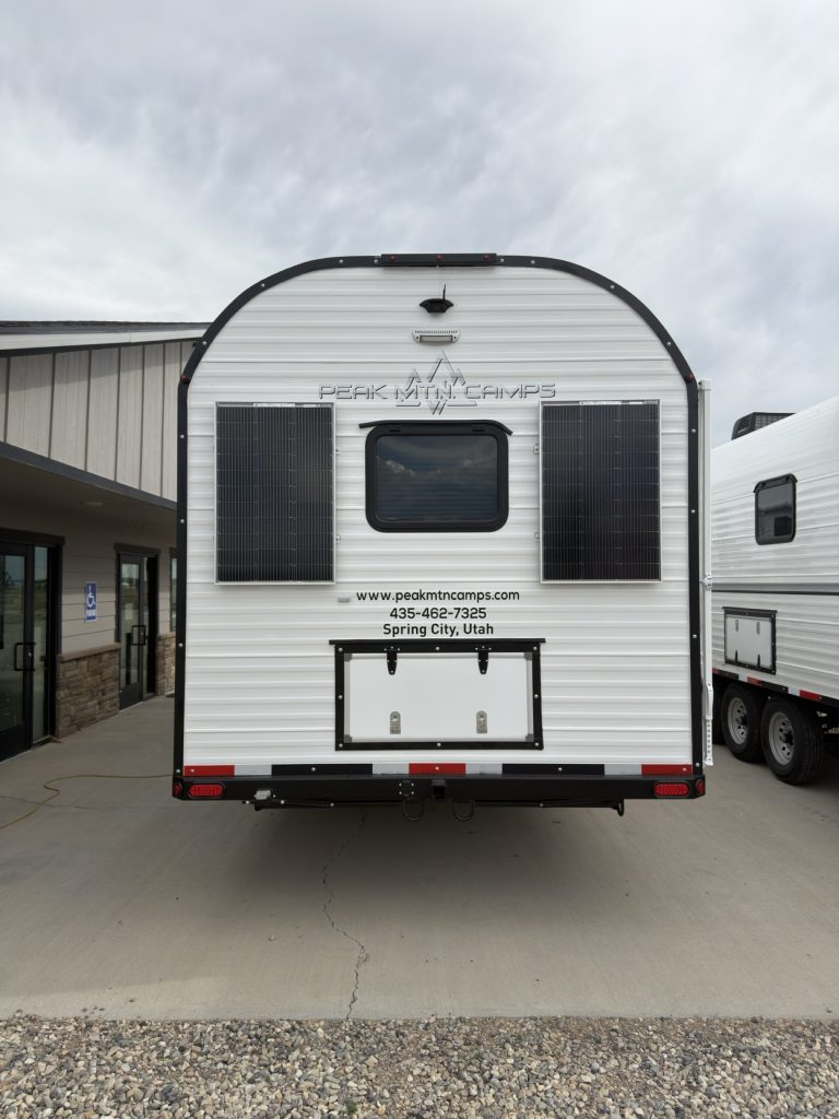 Rear exterior with two solar panels, egress window, and central storage hatch.