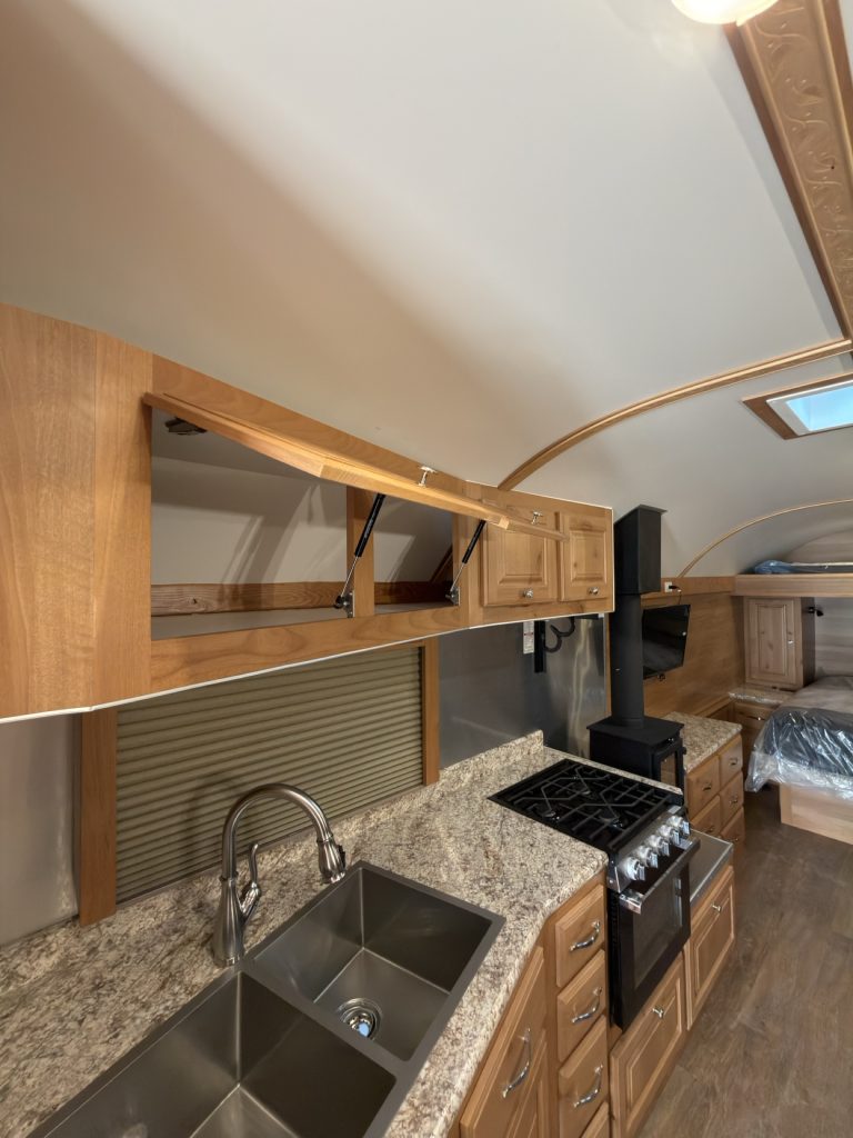 Double stainless steel sink and residential faucet beside the three-burner range.