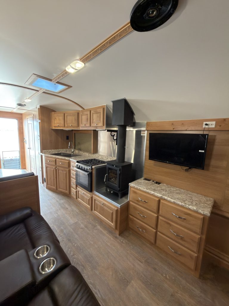 Living area with recliner, wood stove, entertainment cabinet, and wall-mounted TV.