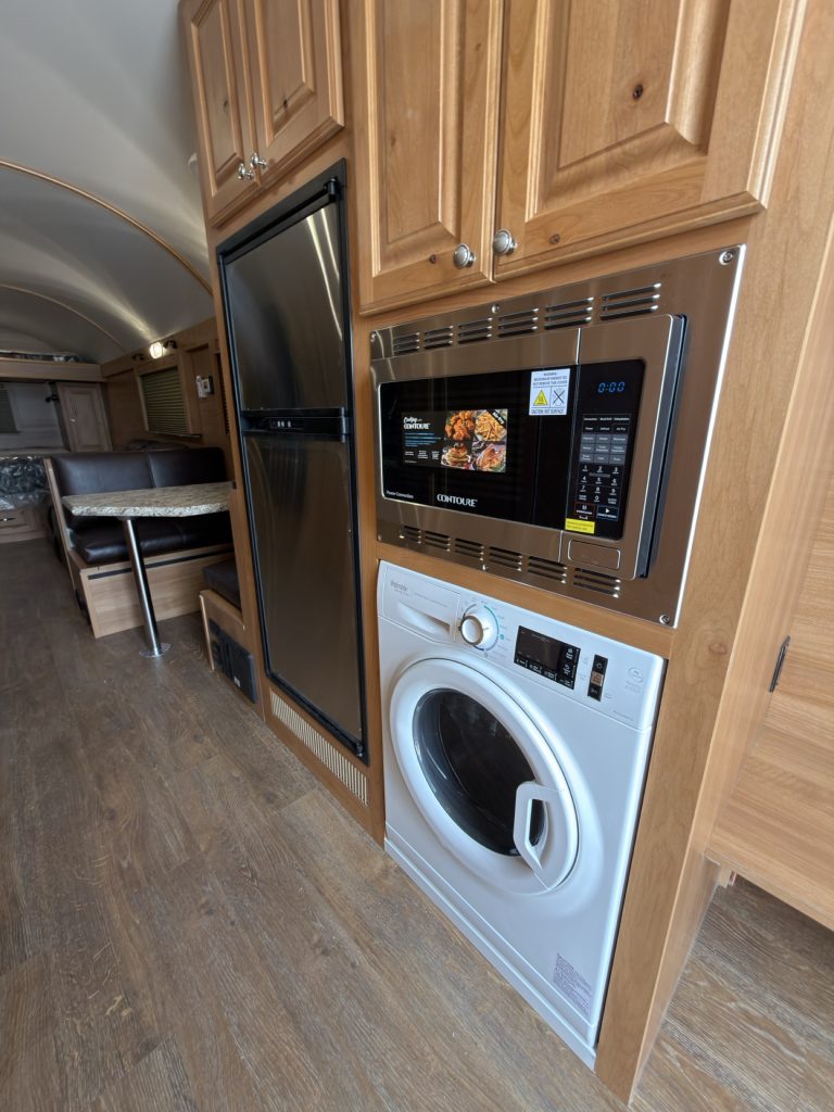 Washer-dryer combo built beneath the microwave and surrounded by hardwood cabinetry.