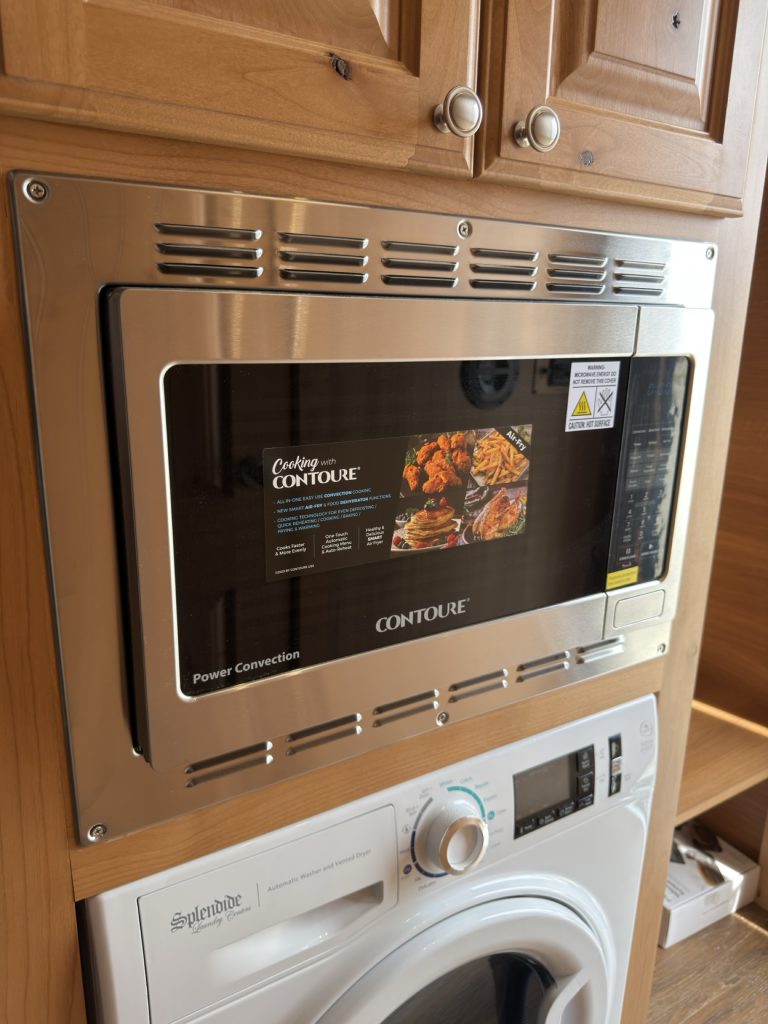 Built-in microwave with air fryer above the front-loading washer-dryer.