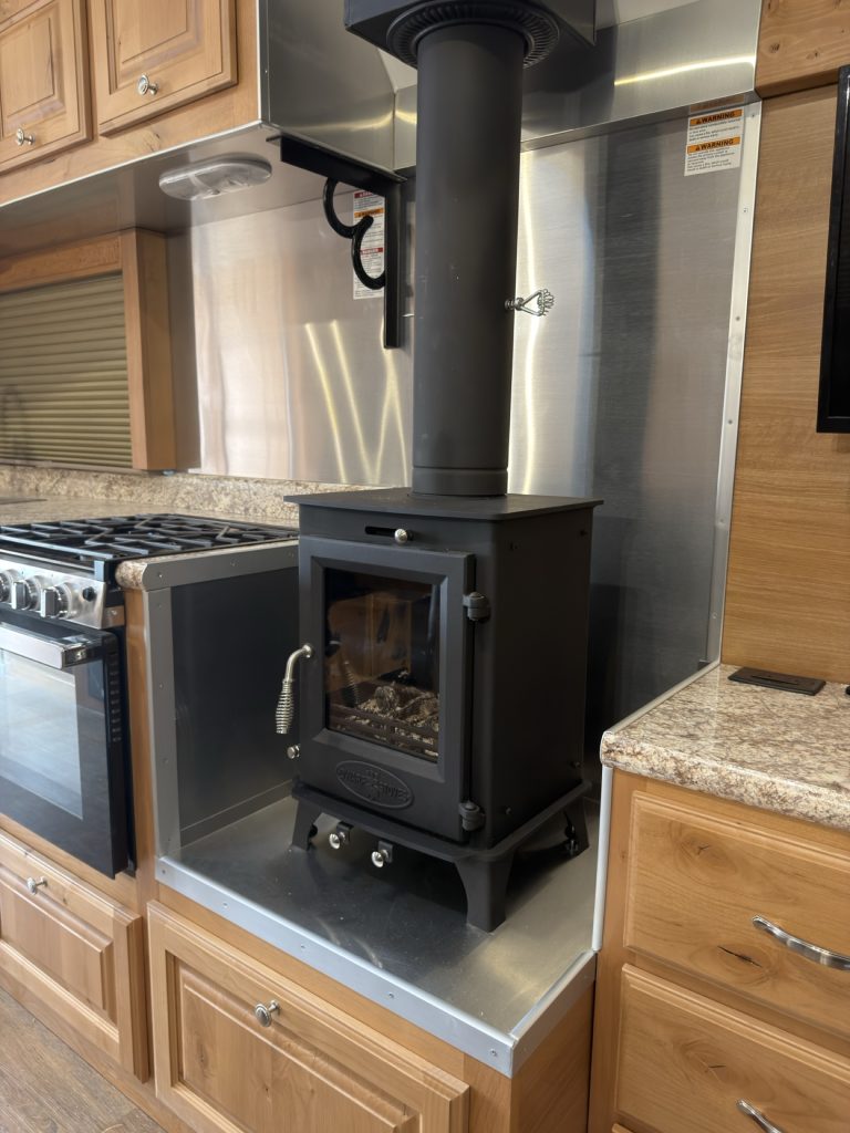 Black wood-burning stove set into fire-lined hardwood cabinetry.