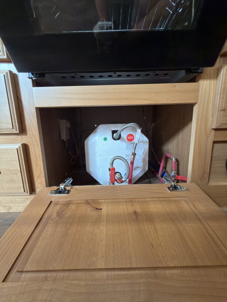 Accessible water heater compartment below the entertainment center