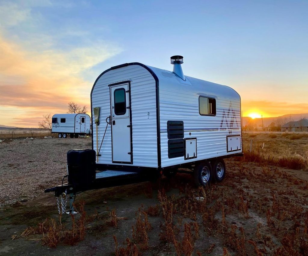 Compact Peak camp trailer parked in open country during a vivid sunset