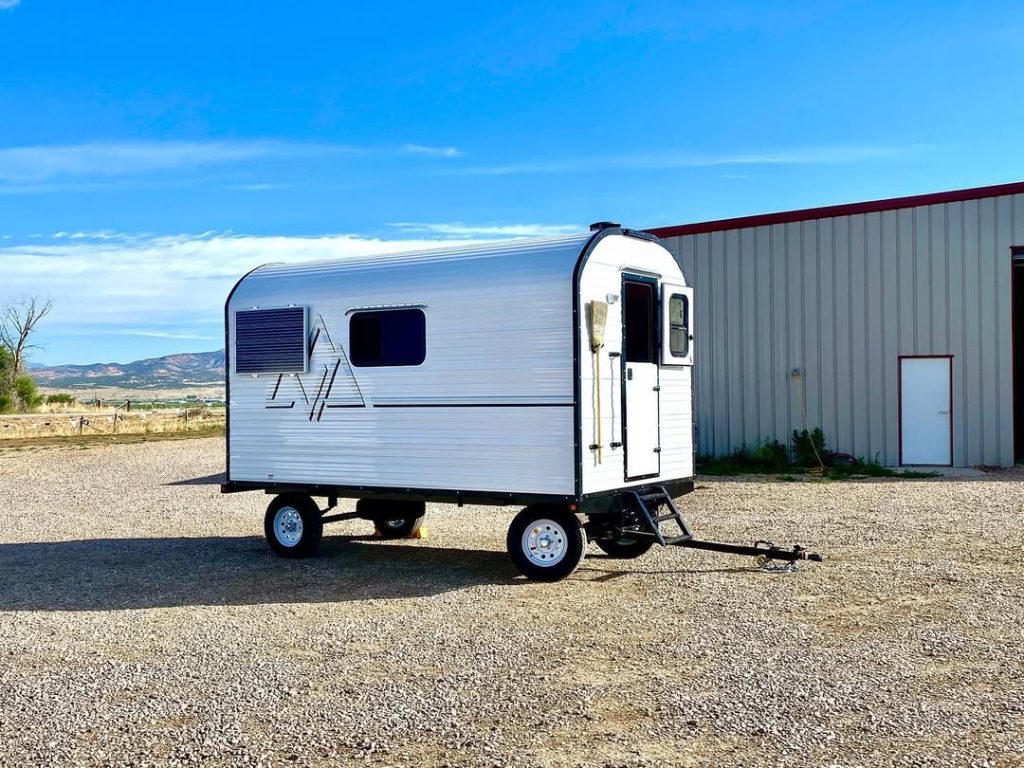 Compact single-axle Peak camp trailer displayed beside the workshop