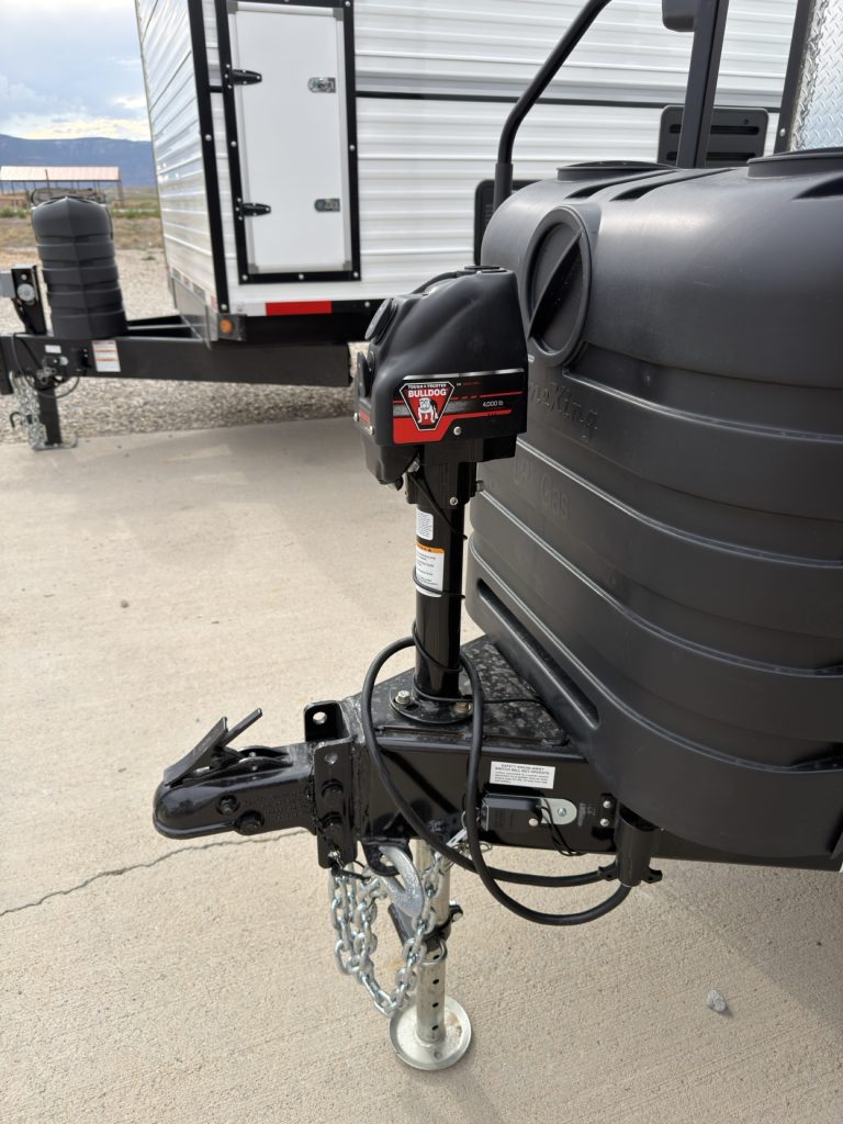 Adjustable coupler, tongue jack, safety chains, and black propane tank cover.