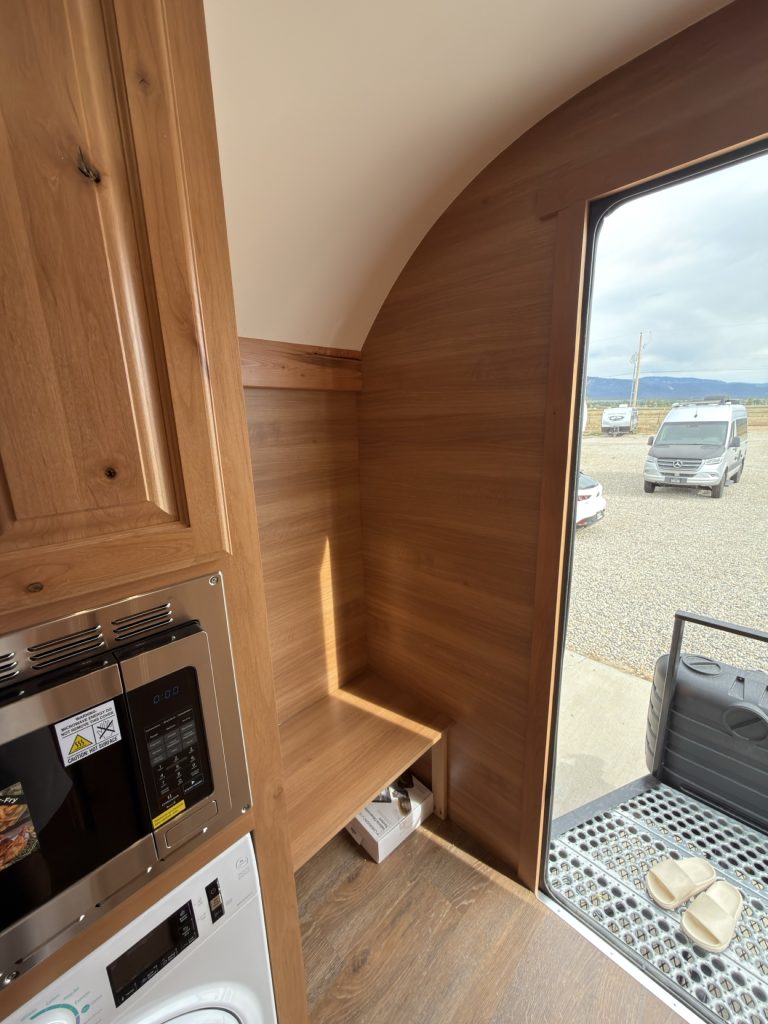 Wood-lined entry alcove with boot bench and open shelf.