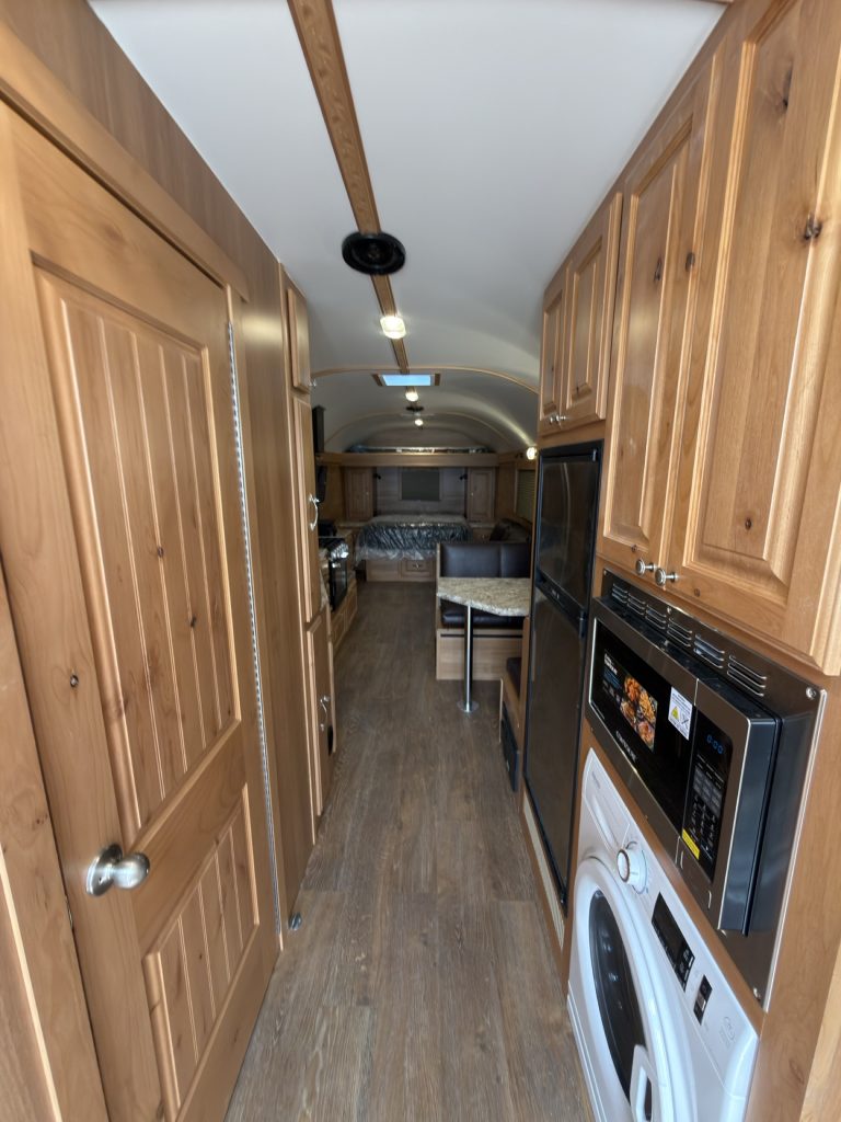 Narrow hallway with hardwood cabinets and washer-dryer leading to the living area.