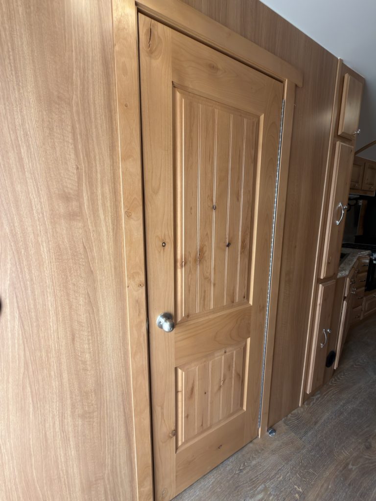 Closed solid hardwood bathroom door with a round metal knob.