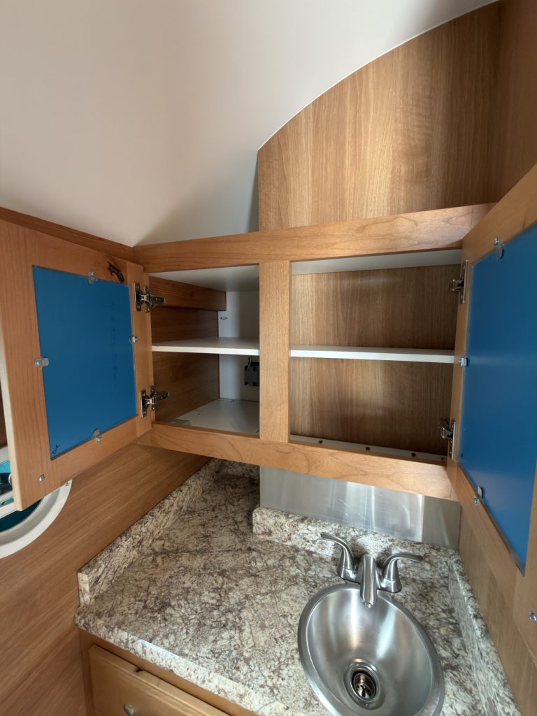Medicine cabinet doors open above the stainless bathroom sink and countertop.