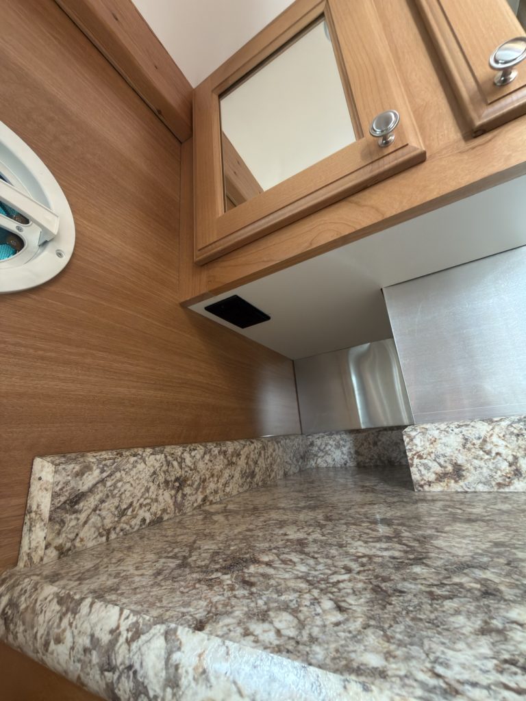 Bathroom vanity features with granite-pattern countertop and mirrored cabinet.