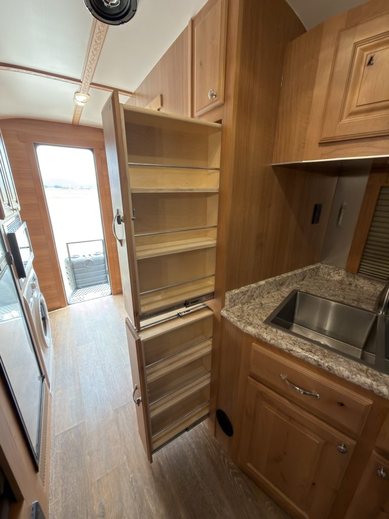 Tall slide-out pantry beside the sink and hardwood kitchen drawers.