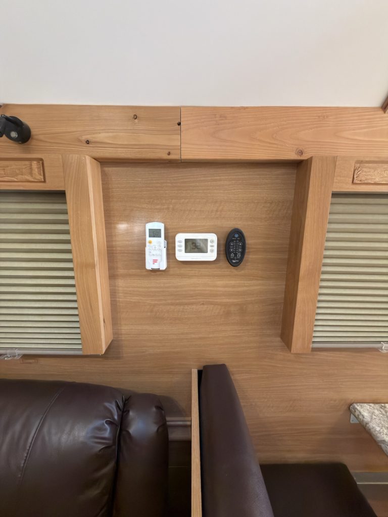 Thermostat and wall controls between two window shades above the recliner.