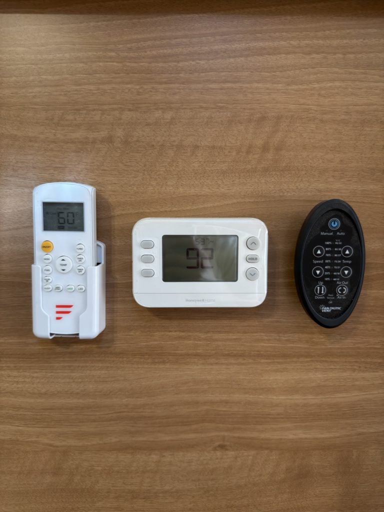 Three wall-mounted climate-control remotes and thermostat.