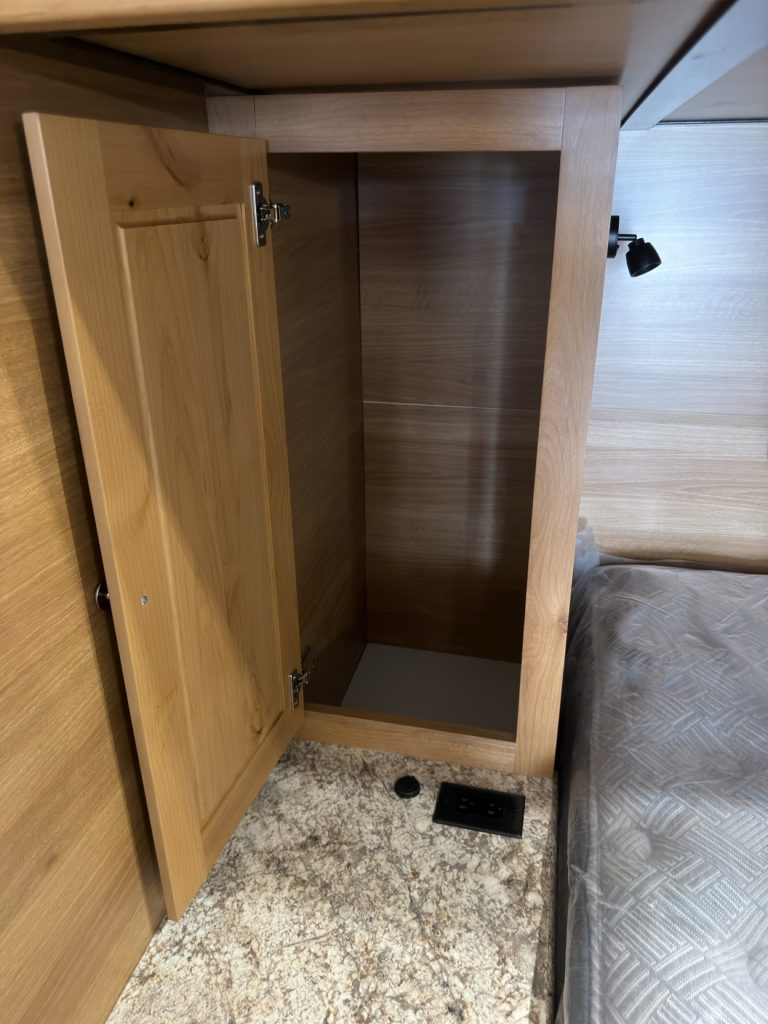 Open wardrobe beside the queen bed with floor vent and granite-pattern shelf.