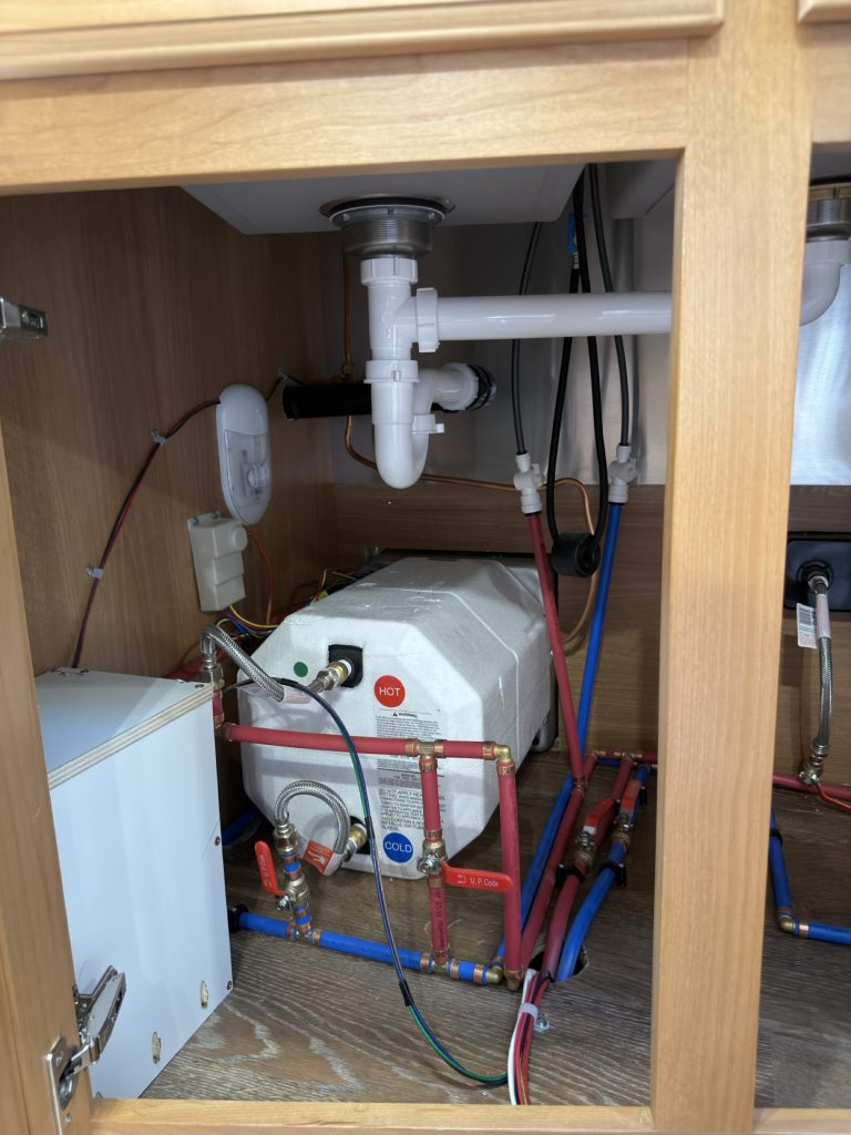Water heater and insulated plumbing beneath the kitchen sink.