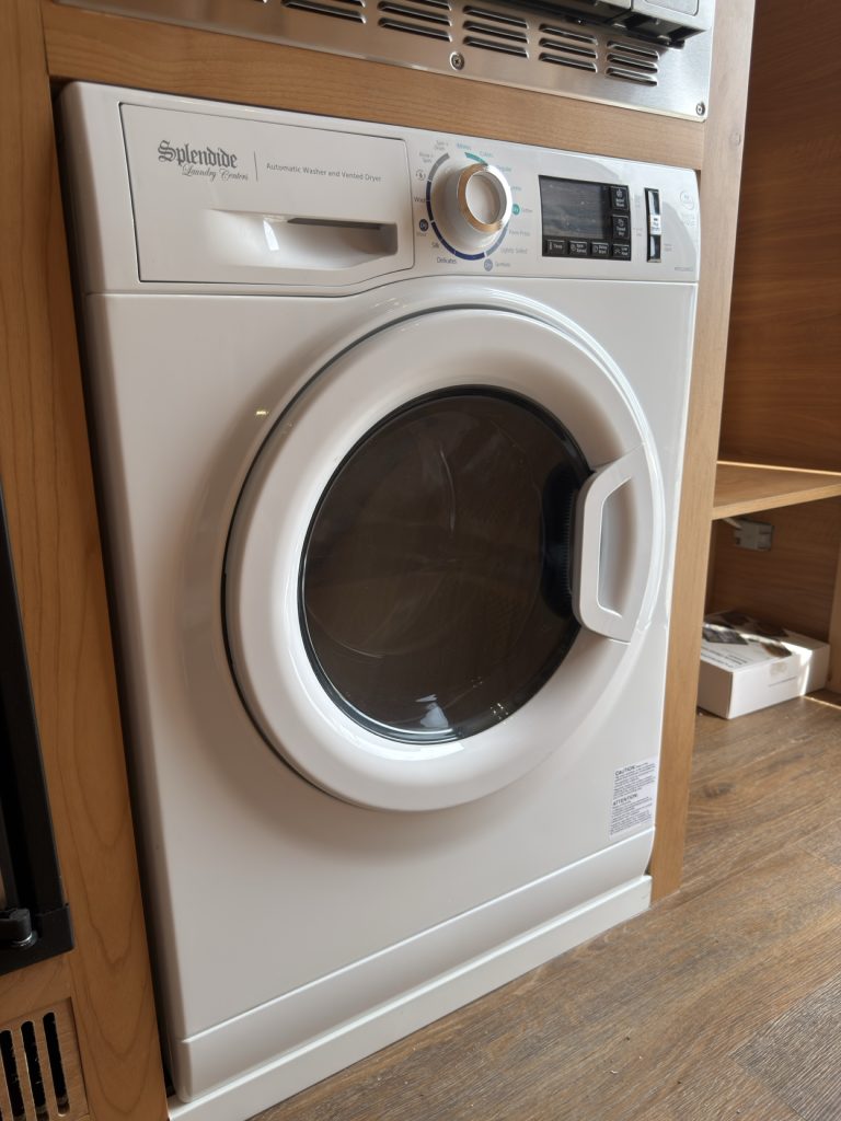 Front-loading washer-dryer with circular glass door.