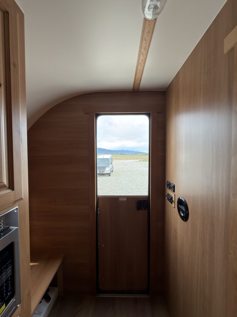 Interior view toward the closed Dutch entry door with light wood paneling and controls.