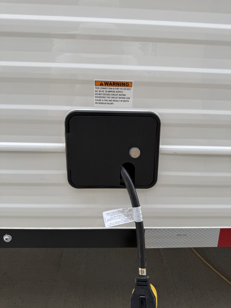 Shore power connection and cable on white exterior siding.