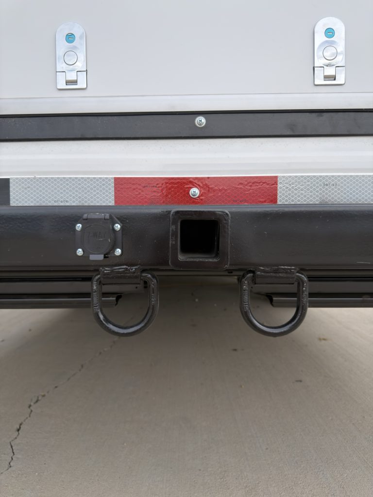 Square rear receiver with paired safety-chain loops below the bumper.