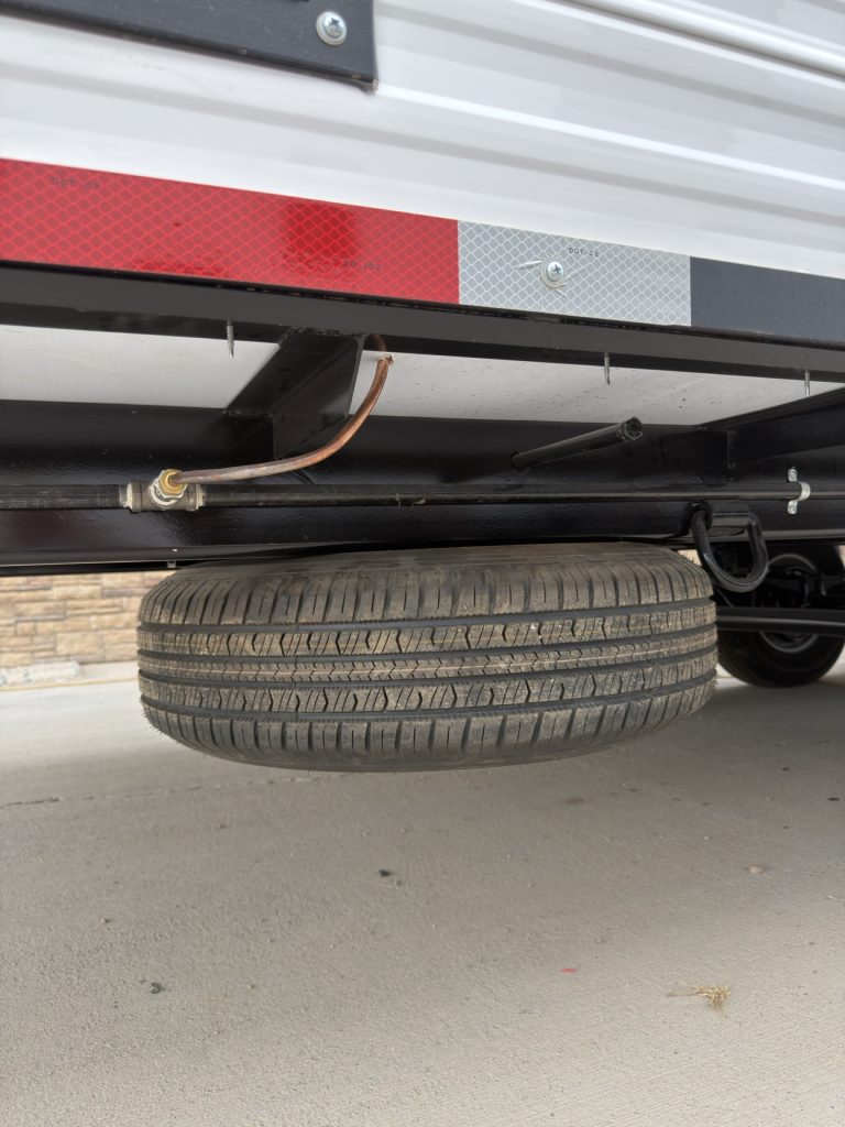 Spare tire mounted horizontally beneath the rear frame.