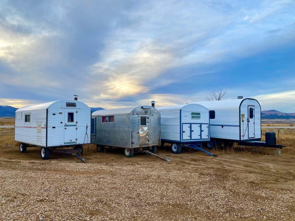 Three custom camp trailers parked together beneath dramatic evening clouds