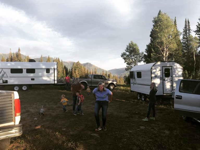 Family members gathered between two Peak camp trailers in the mountains