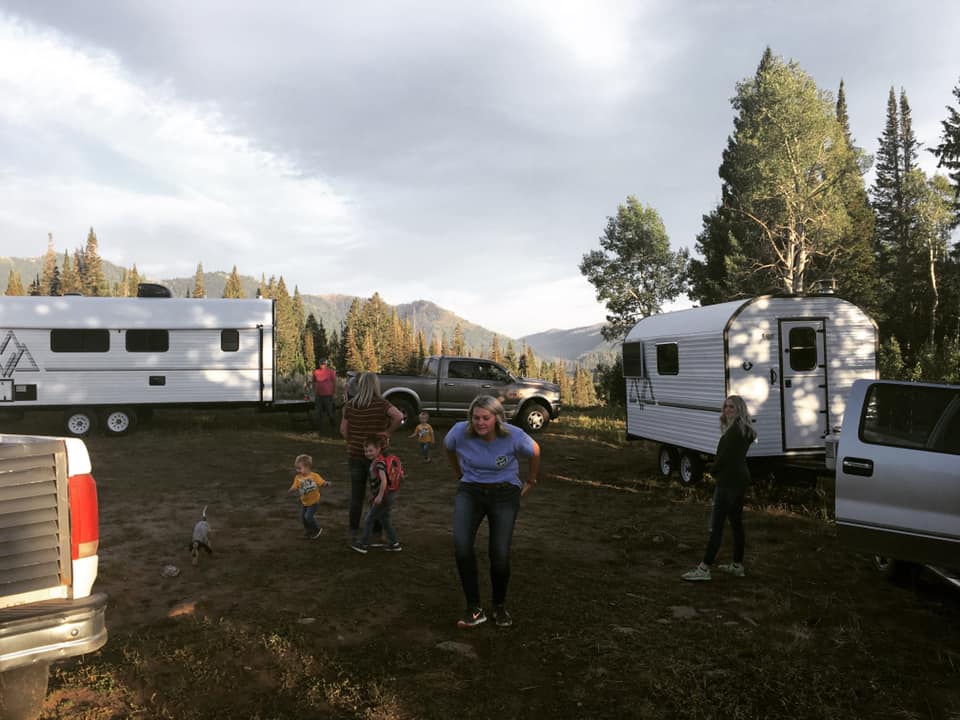 Family members gathered between two Peak camp trailers in the mountains