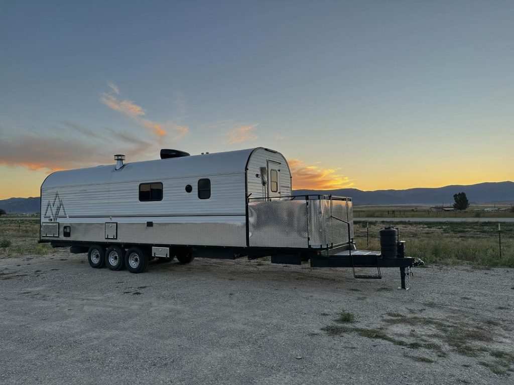 Peak camp trailer parked on open range as evening light fades
