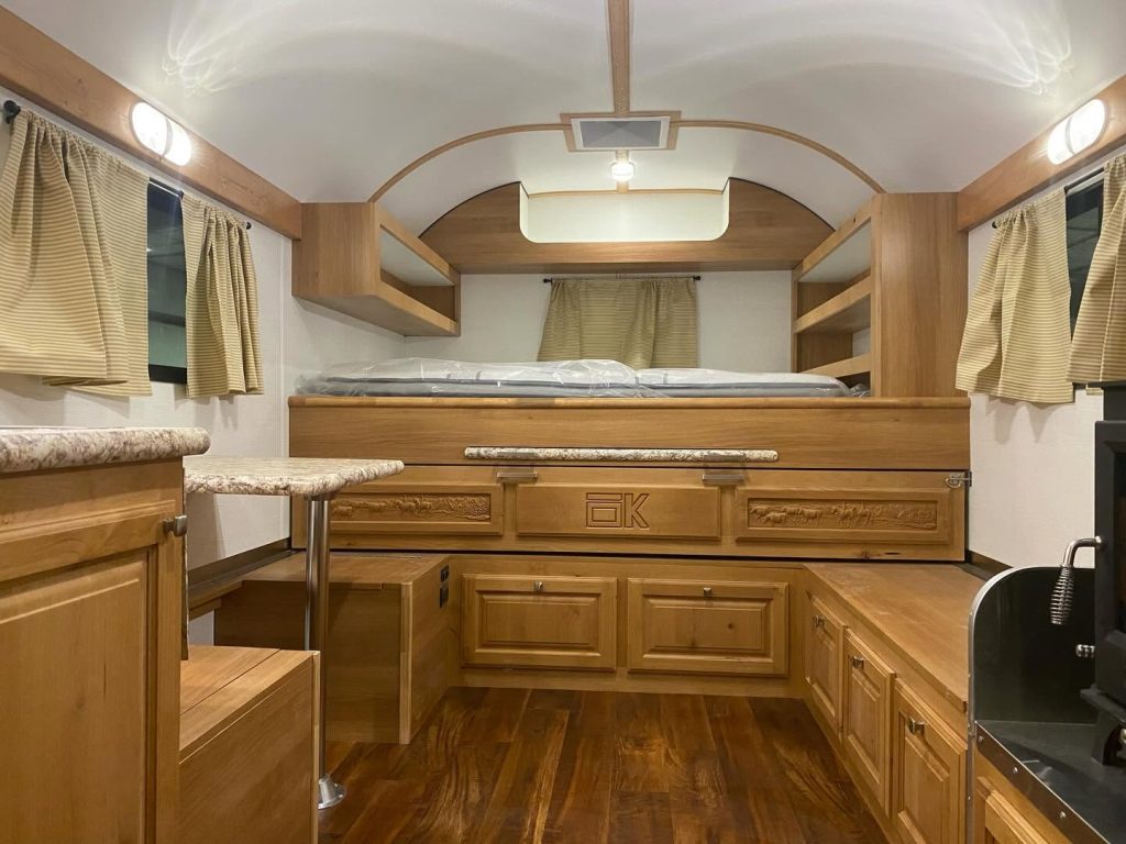 Peak camp interior with a raised sleeping platform, built-in seating, storage, and wood cabinetry
