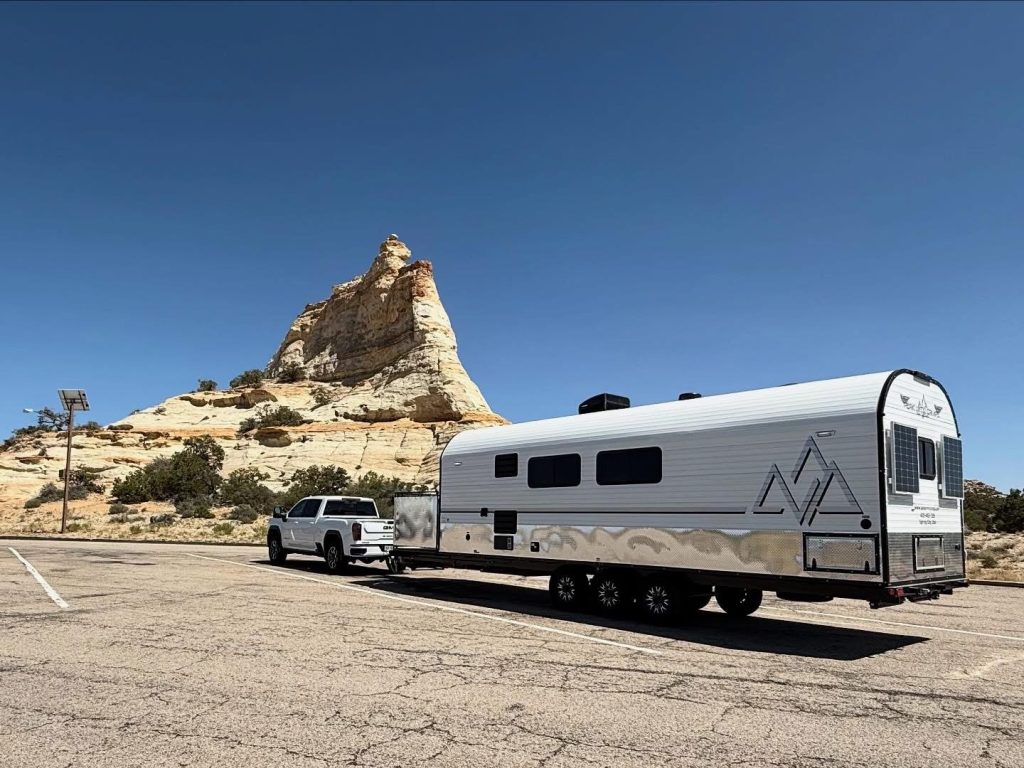 Pickup towing a Peak camp trailer past a dramatic Utah rock formation