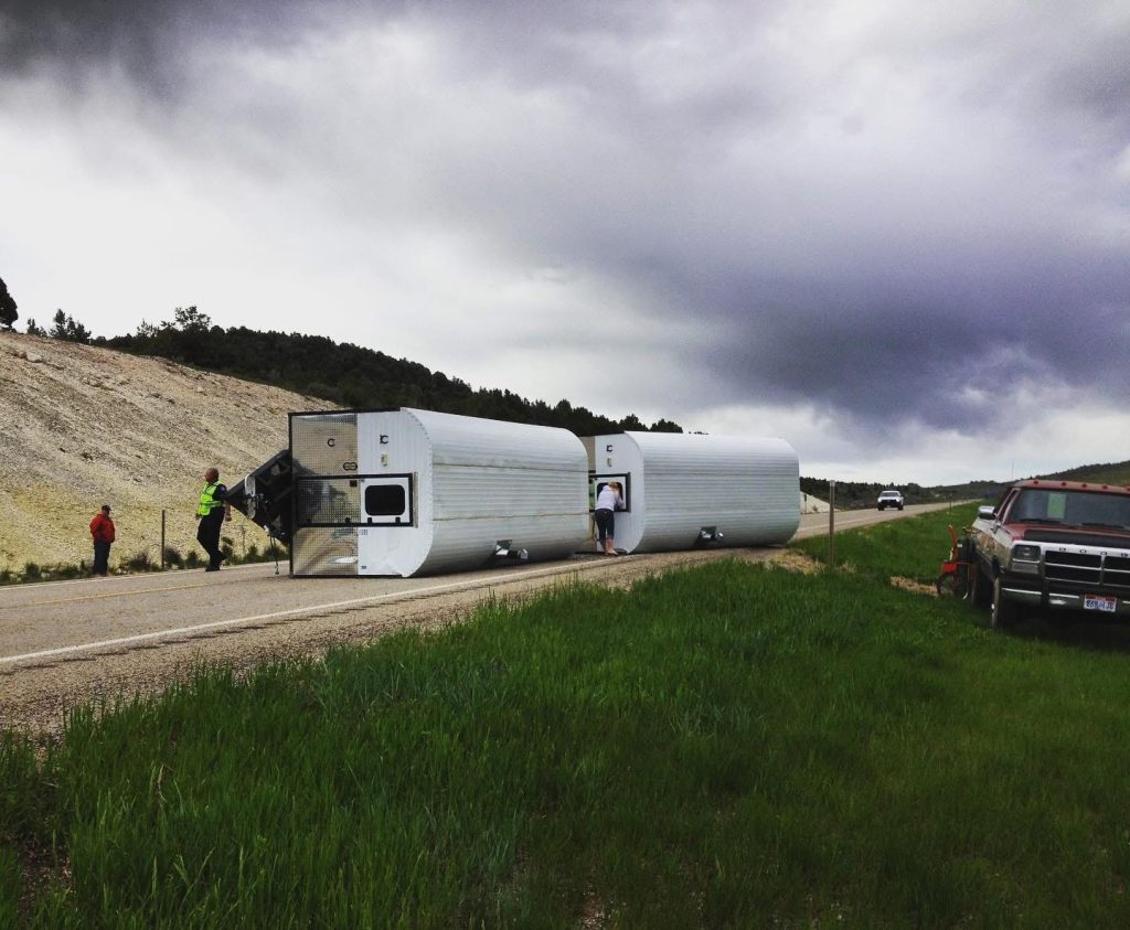 Several camp trailers parked together in green open country with horses nearby