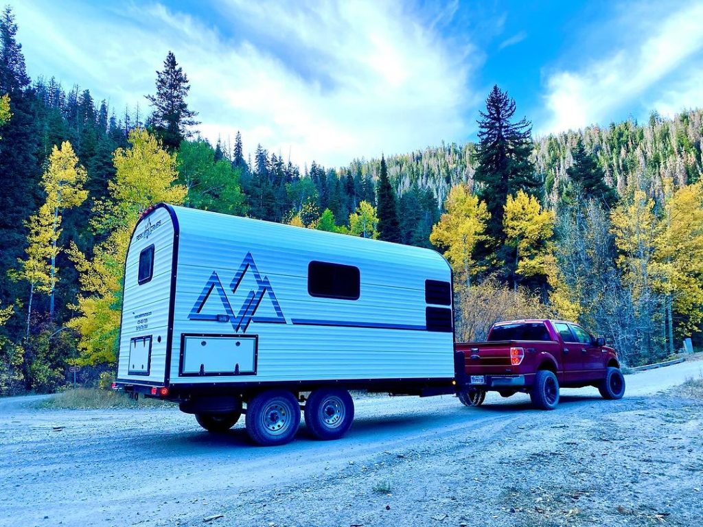 Pickup and Peak camp trailer surrounded by colorful autumn mountain trees