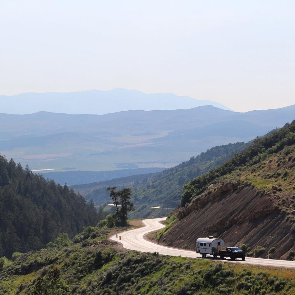 Distant pickup and camp trailer traveling along a winding mountain pass