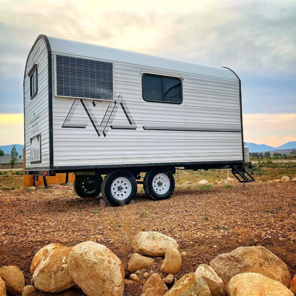 Rear and side profile of a Peak camp trailer on rocky open range