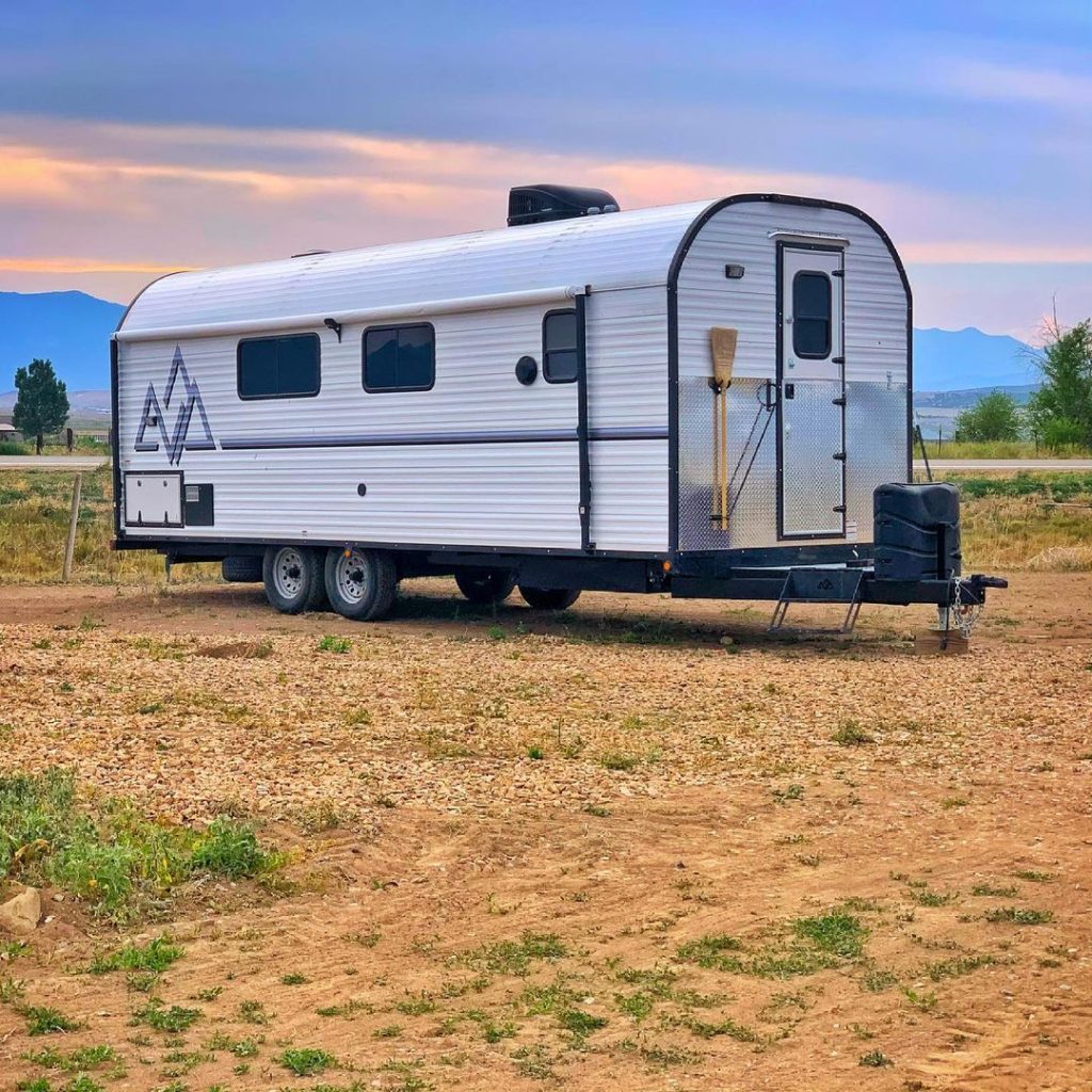 Side profile of a Peak camp trailer set up in open desert country