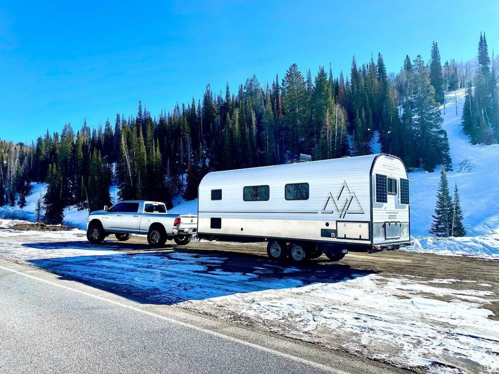 Pickup towing a Peak camp trailer along a snowy mountain road