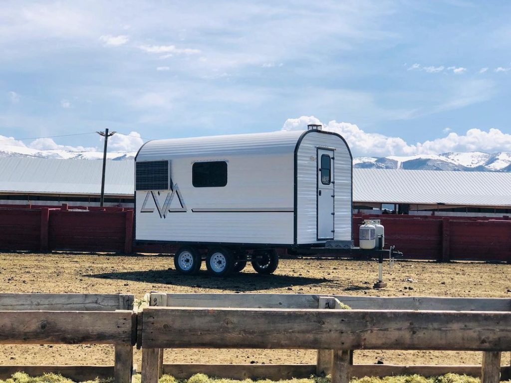 Peak camp trailer displayed with snowcapped mountains rising in the distance