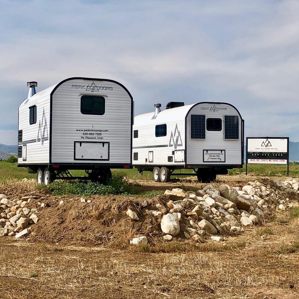 Several Peak camp trailers parked together on rocky open ground