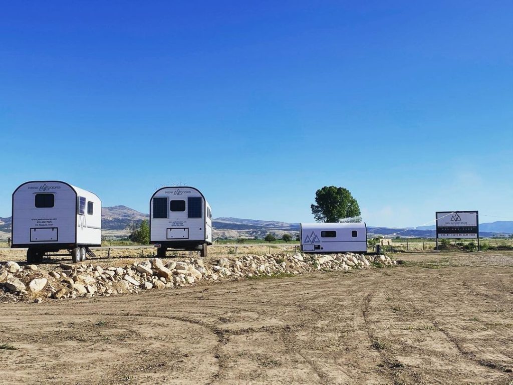 Three Peak camp trailers displayed together in an open gravel lot