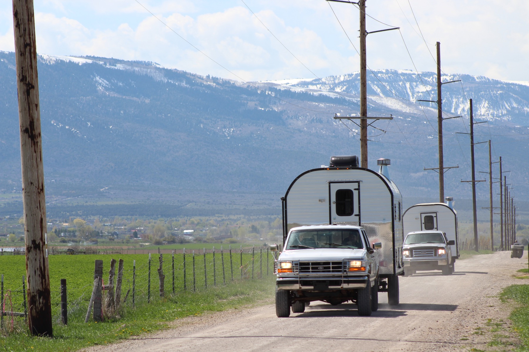 Two Peak Mountain Camps traveling a rural road below snow-covered mountains
