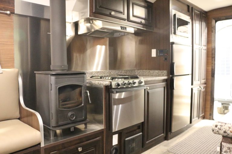 Peak Mountain Camp interior with hardwood cabinetry, kitchen appliances, and wood-burning stove