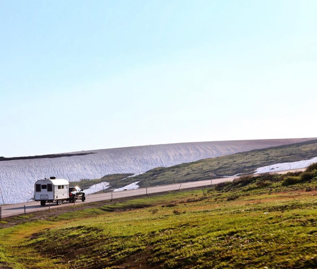 Distant Peak camp trailers parked in broad treeless country beneath cloudy skies