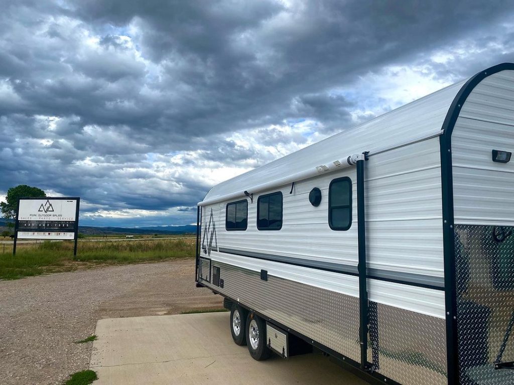 Peak camp exterior displayed under dramatic storm clouds near the workshop