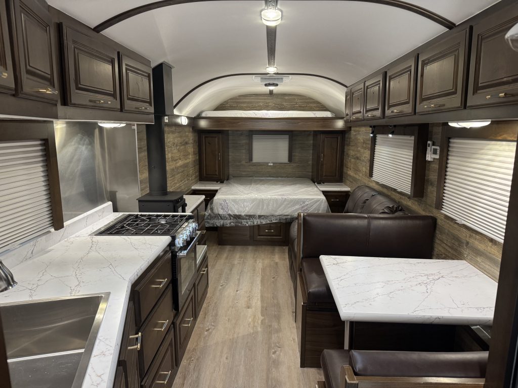 Wide view of the untitled X35 camp interior showing the kitchen, dinette, recliners, and north/south bed