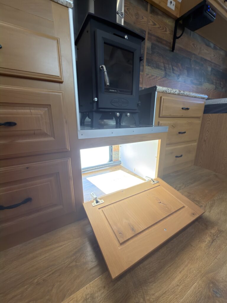 Image of the storage compartment beneath wood stove of Gail Camp #131.