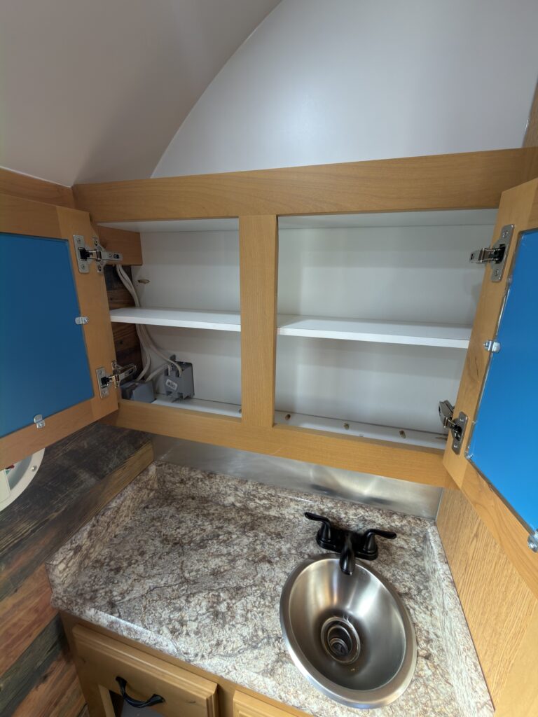Image of the open bathroom upper cabinets of Gail Camp #131.
