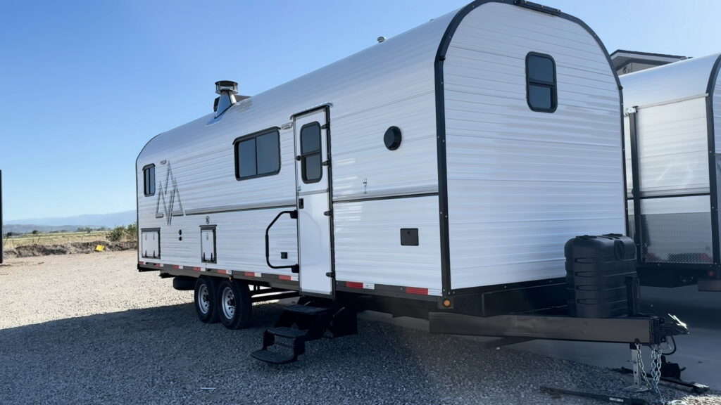 Front three-quarter view of Plankis Camp #124 showing the curved front wall, side entrance, and trailer tongue.