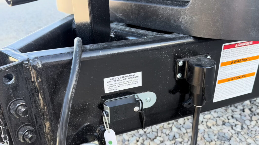 Trailer breakaway switch and attached cable mounted on the black tongue frame of Plankis Camp #124.